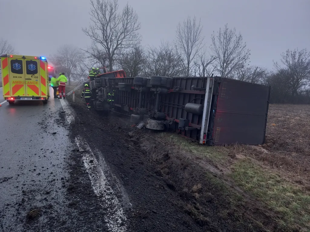 Převrácený kolos u Podbřezí: Řidič vyvázl bez zranění, vyproštění kamionu si ale vyžádalo úplnou uzavírku tahu I/14