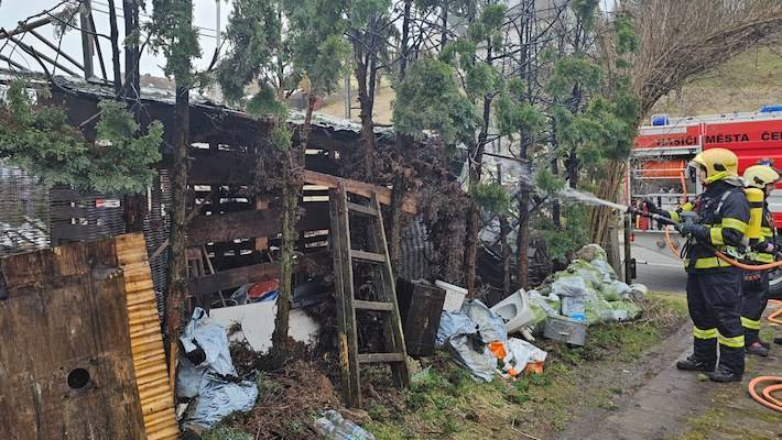 Přístřešek a vedle zasazené keře v plamenech